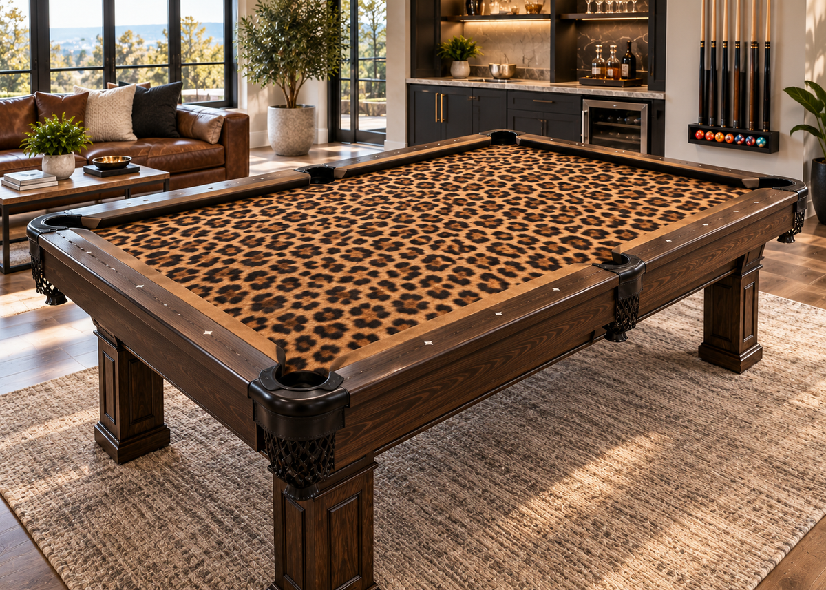 Leopard print custom pool table felt displayed on a dark wood billiards table in a bright luxury game room with sofa, bar area, and large windows.
